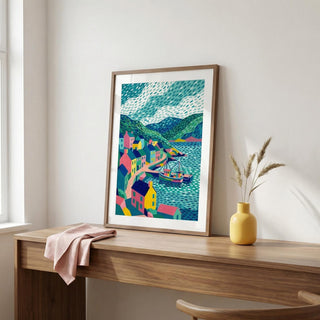 Framed colorful artwork on a wooden desk with a yellow vase and pink cloth.