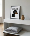 Framed picture of a dog with 'DOGUE' text on a white shelf with a vase and pillow.