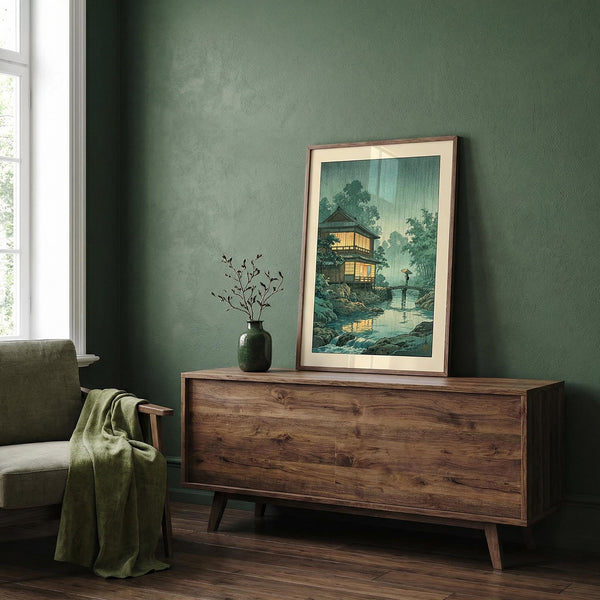 Wooden sideboard with a framed artwork and vase against a green wall.