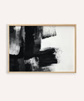 Abstract black and white art print in a wooden frame on a white wall