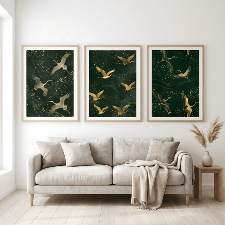 Set of 3 art prints above a sofa with beige cushions featuring golden cranes on dark green backgrounds