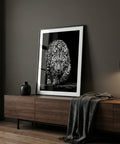 Framed artwork of a leopard on a wooden sideboard against a dark wall.