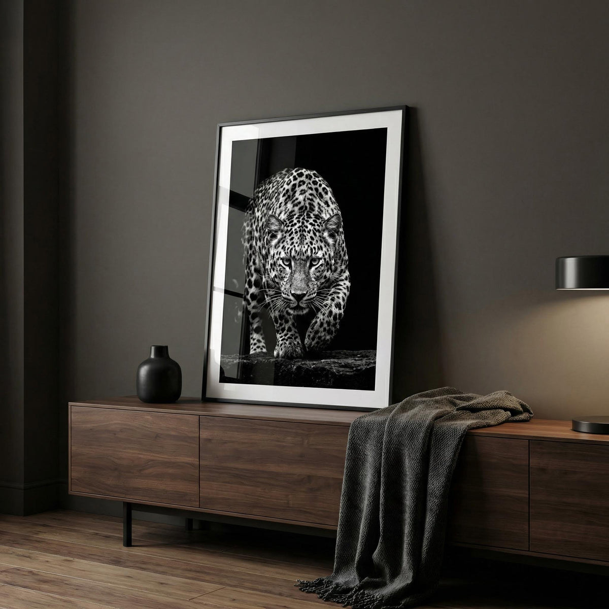Framed artwork of a leopard on a wooden sideboard against a dark wall.