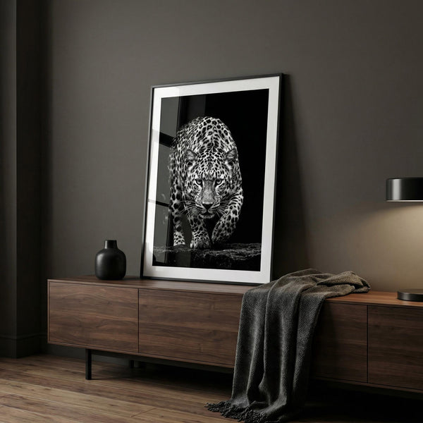 Framed artwork of a leopard on a wooden sideboard against a dark wall.