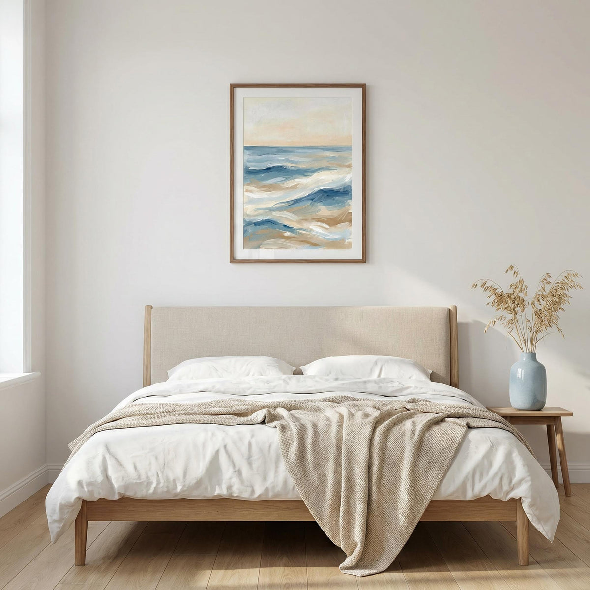 Beige bed with white bedding and a beige blanket in a room with a painting on the wall.