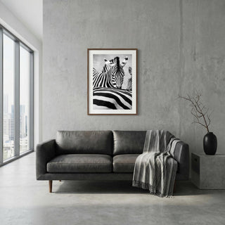 Modern living room with a gray sofa, zebra print artwork, and a vase.