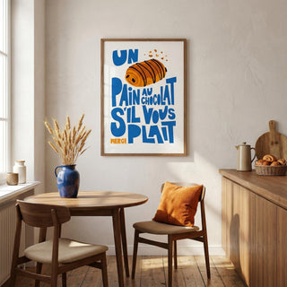 Dining room with a framed Pain Au Chocolat Wall Art, wooden table, chairs, and a vase.