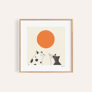 Framed print close-up of minimalist black and white cats looking at an orange sun