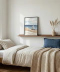 Cozy bedroom with a bed, shelf with decor, and wall art of a small sailboat