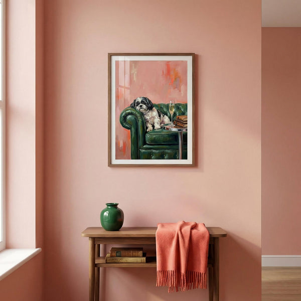 Framed artwork of a dog on a green couch in a room with pink walls, a wooden side table, and a green vase.
