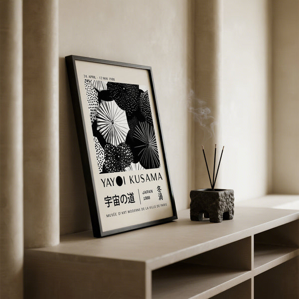 Framed winter wall art by Yayoi Kusama on a shelf with a minimal background
