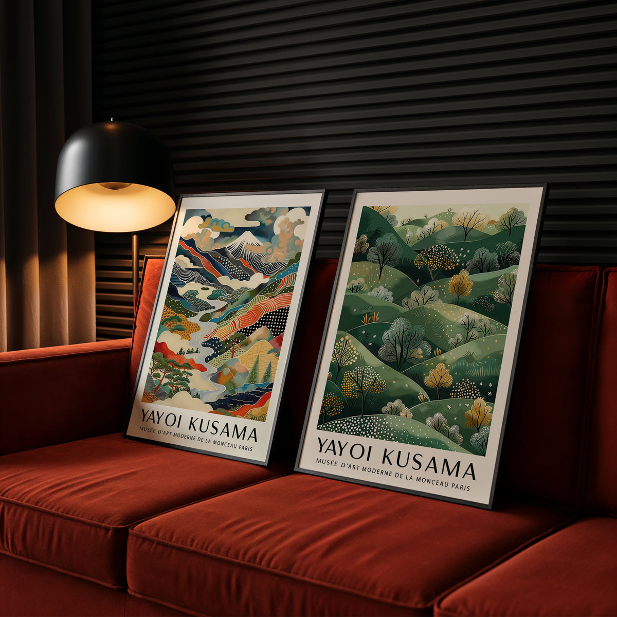 Two framed Yayoi Kusama artworks on a red couch with a lamp in the background.