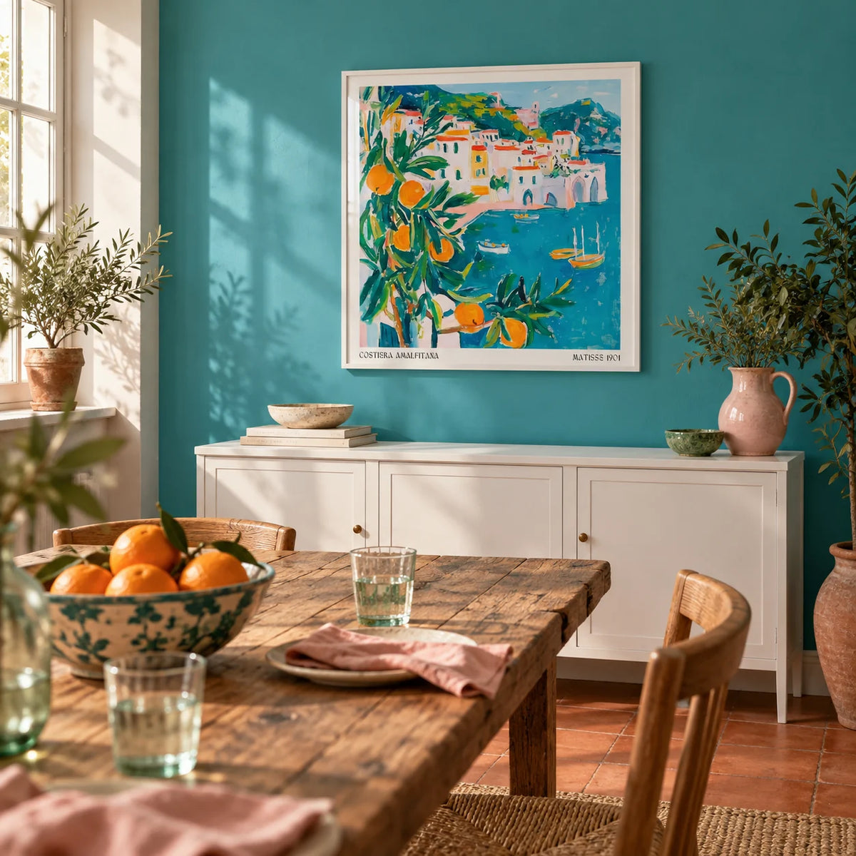Amalfi Coast Print, framed on the wall of a bright dining room with a turquoise painted wall and a plain terracotta floor