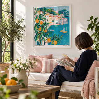 Amalfi Coast Print, framed on the wall of a bright garden room with white walls and plants in a living room