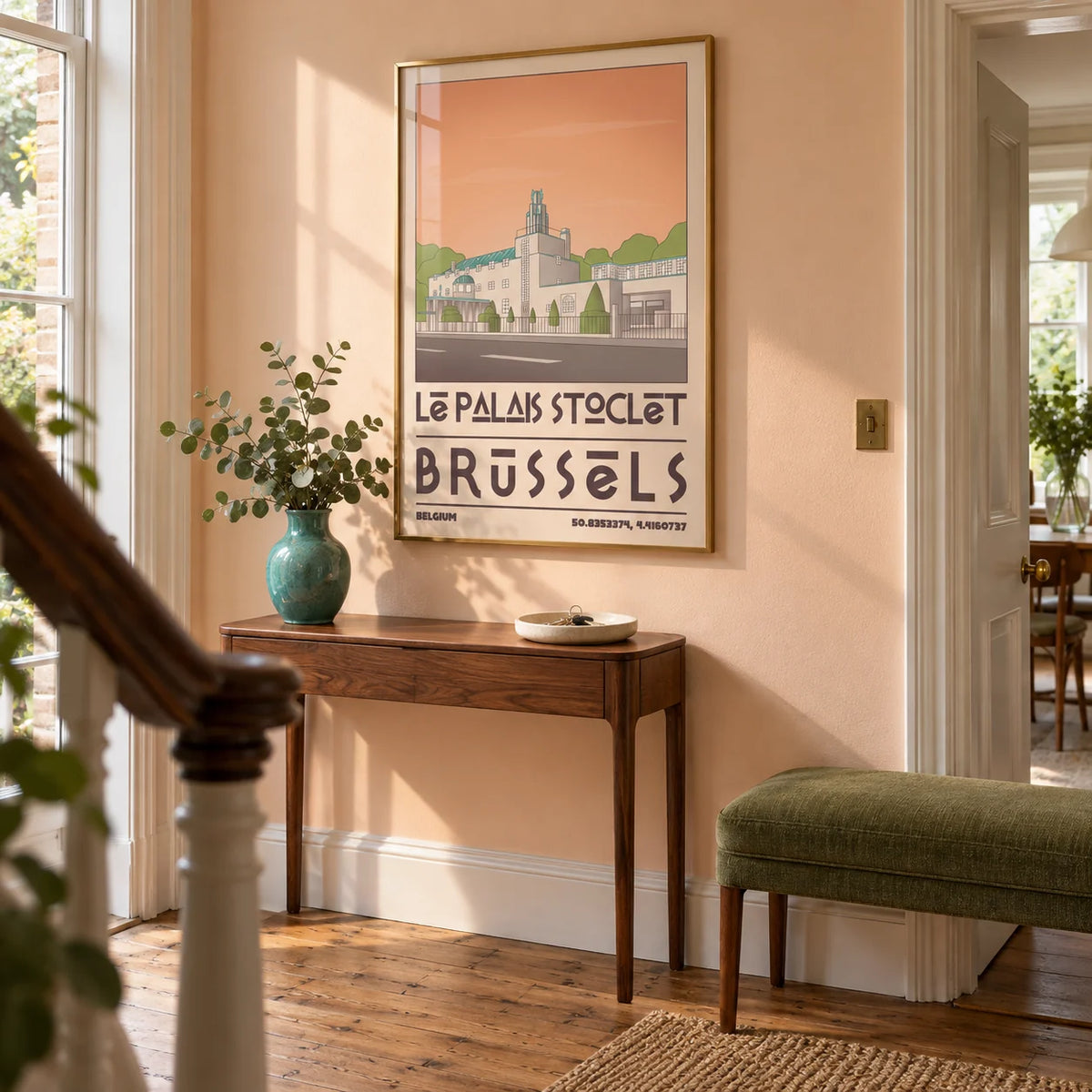 Art Deco Brussels Print, framed on the wall of a welcoming hallway in a renovated British terraced house with pale peach walls and restored timber floorboards