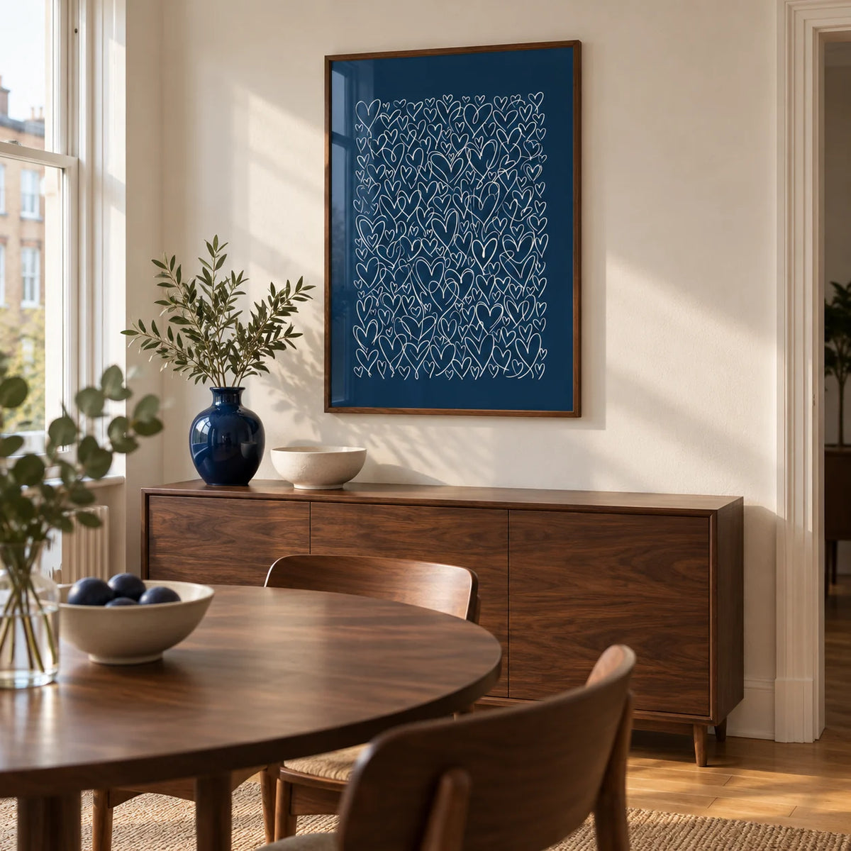 Art with Hearts, framed on the wall of a compact contemporary dining room in a UK city flat with ivory walls and walnut furniture