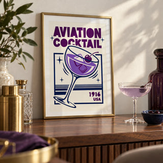 Aviation Cocktail Print, a small A4 framed print leaning on a shelf in a kitchen