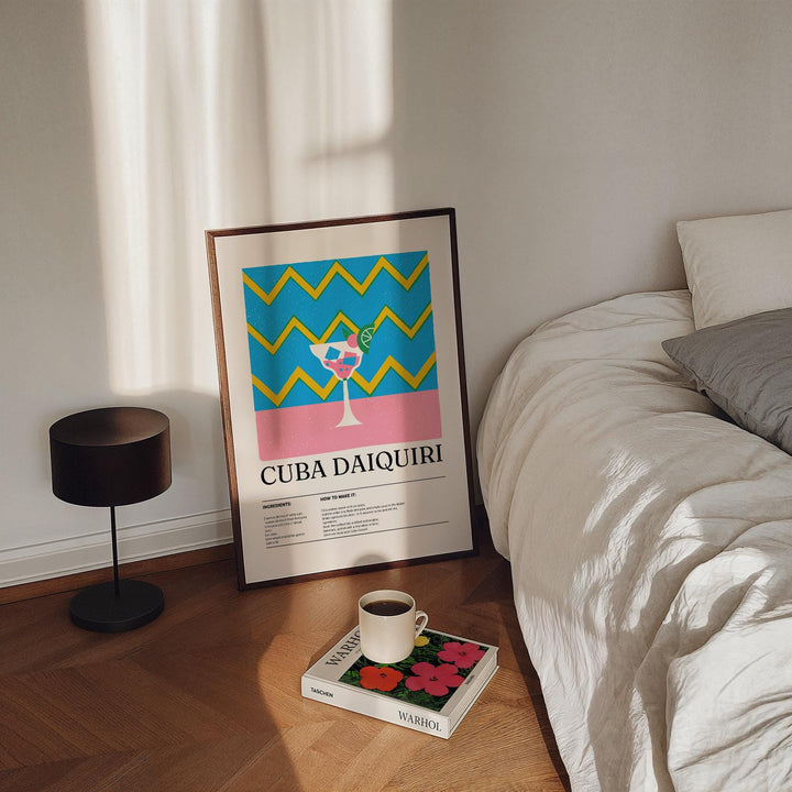 Print leaning on floor showing Alcohol Artwork with a colourful daiquiri cocktail next to a bed and lamp