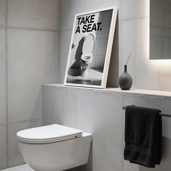 Funny bathroom art saying “Take a Seat” above modern toilet.