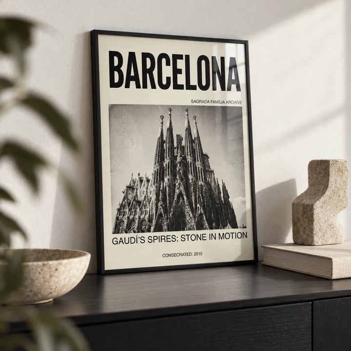 Barcelona Architecture Poster, a small A4 framed print leaning on a black shelf in a living room