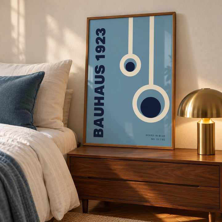Bauhaus Posters, a framed print leaning on a walnut bedside chest in a calm mid-century bedroom