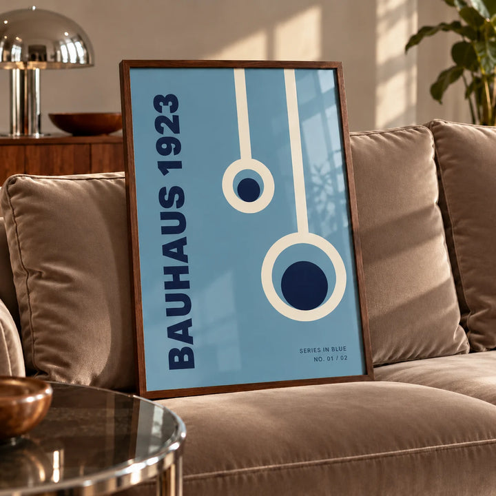 Bauhaus Posters, a framed print leaning on a velvet sofa in a living room