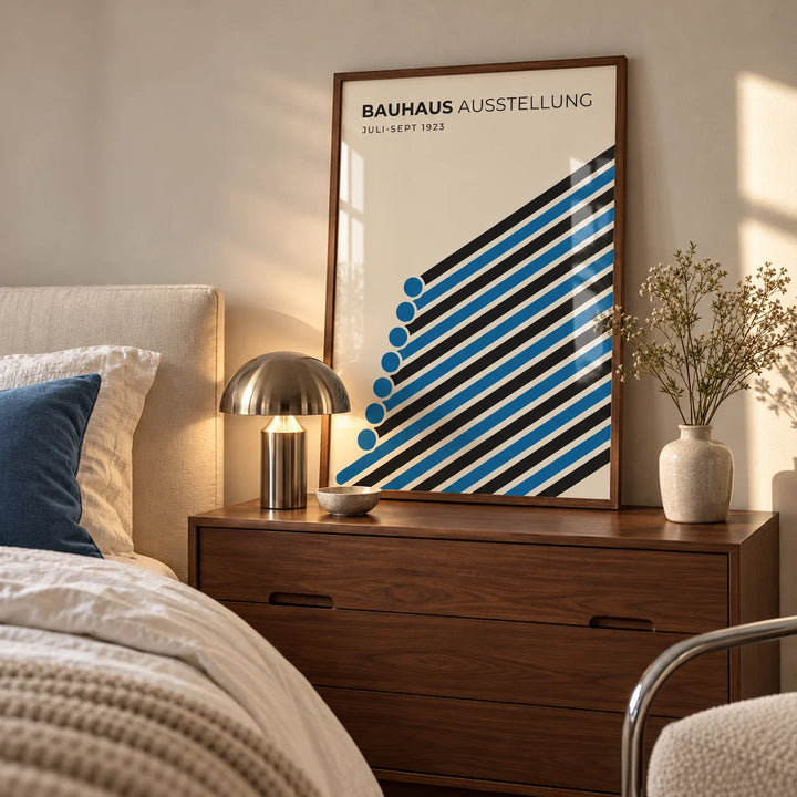 Bauhaus Print, a framed print leaning on a walnut bedside chest in a calm mid-century bedroom