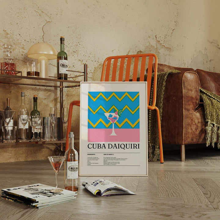 Print leaning on floor of pop-art daiquiri cocktail with blue and yellow zigzags near an orange chair in a living room