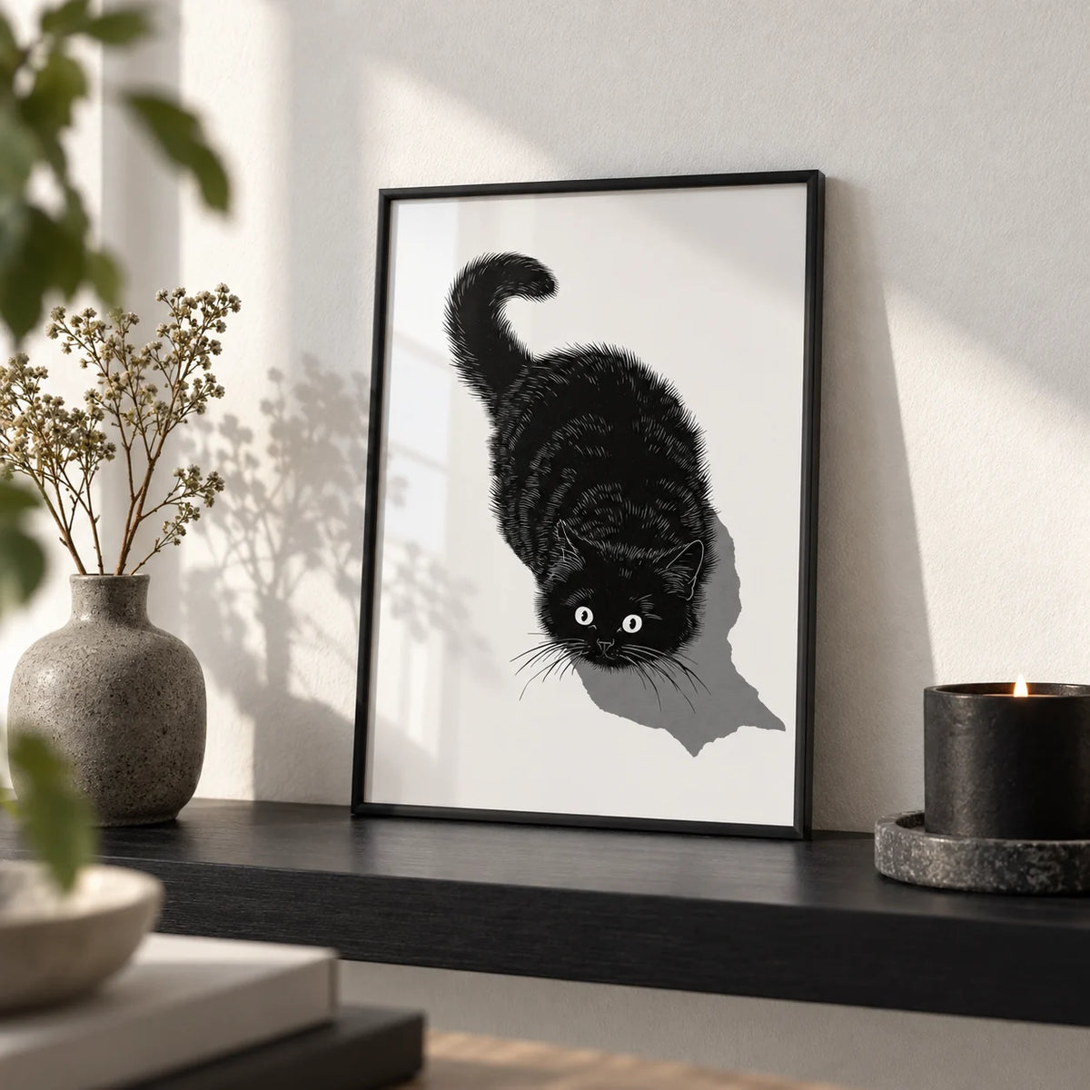 Black Cat Print, a small A4 framed print leaning on a black shelf in a living room