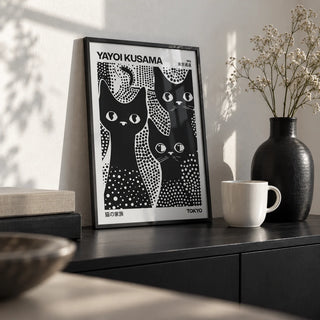 Black Cats Poster, a small A4 framed print leaning on a black sideboard in a living room