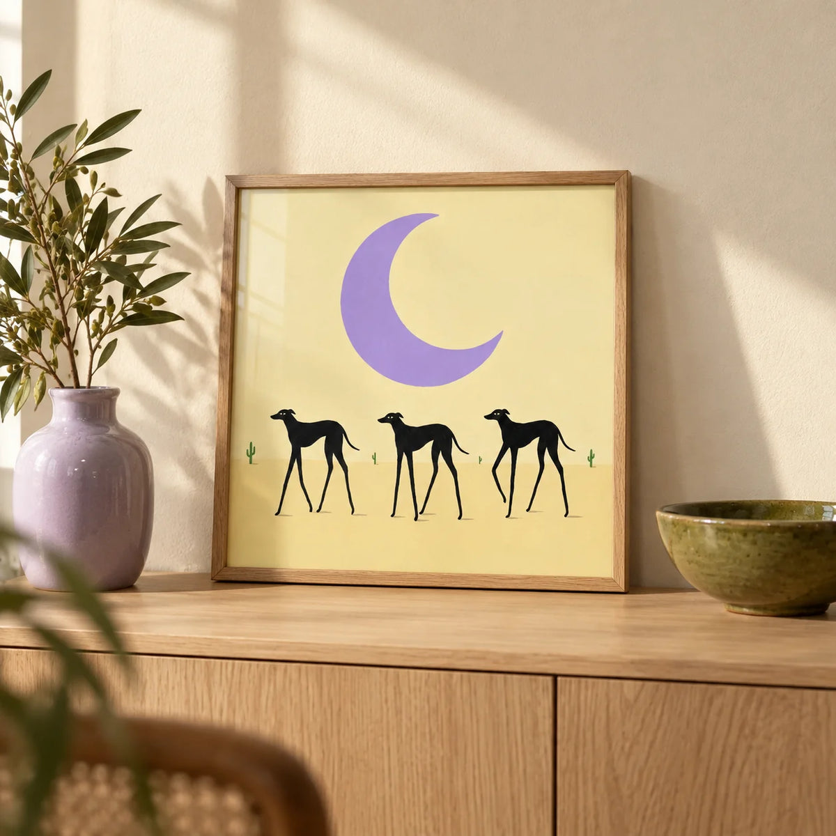 Black Dog Art Print, a small A4 framed print leaning on a pale oak sideboard in a living room
