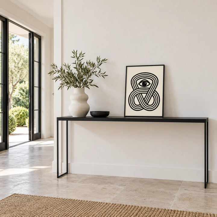 Black Eye Poster, a small A4 framed print leaning on a black side table in a hallway