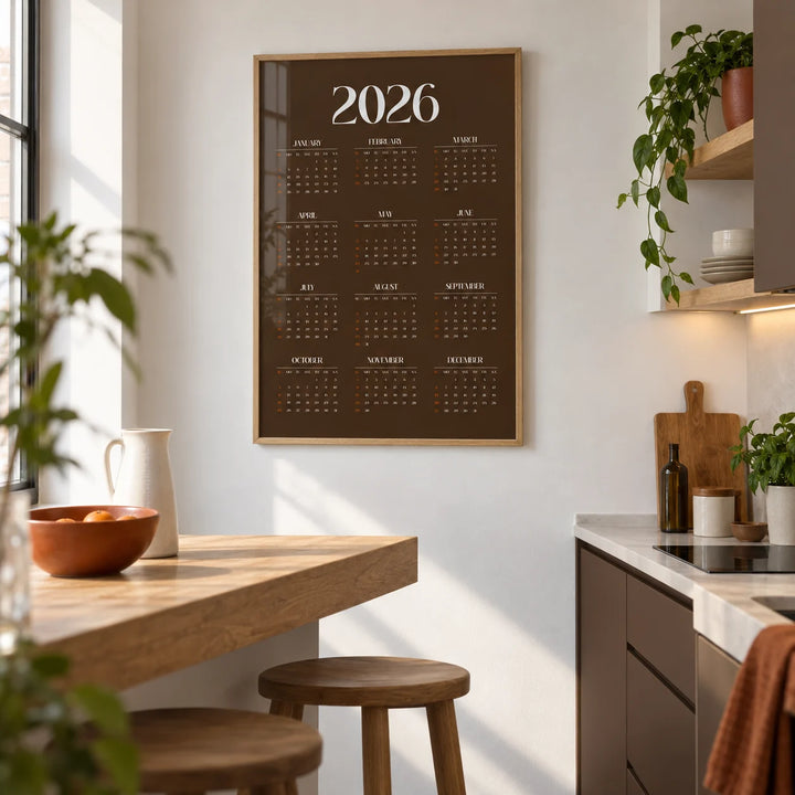 Brown Calendar Print, framed on the wall of a compact modern kitchen in a first flat (22-28) with plain white walls and chocolate brown lower cabinets