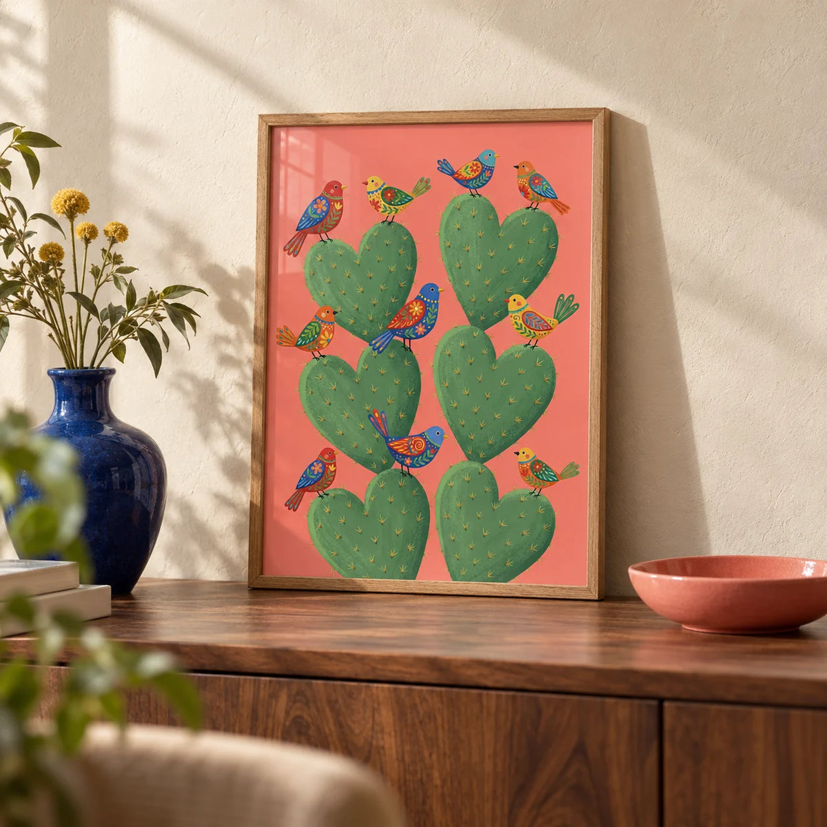 Cactus Heart Poster, a small A4 framed print leaning on a walnut sideboard in a living room