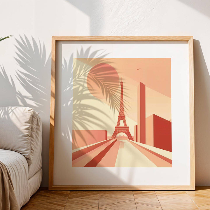 Framed Eiffel Tower poster wall art in bauhaus style with pink and beige tones leaning on wooden floor next to cream sofa
