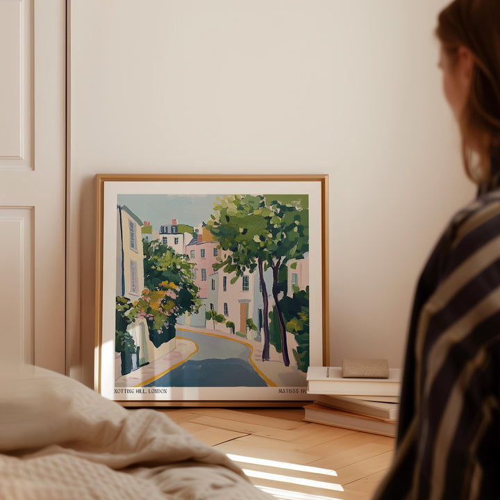 Notting Hill poster leaning on floor by books with pastel colours and a tree