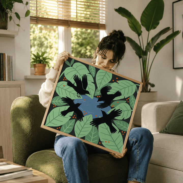 Framed Crows Art Print held by person showing black crows with green leaves and blue centre