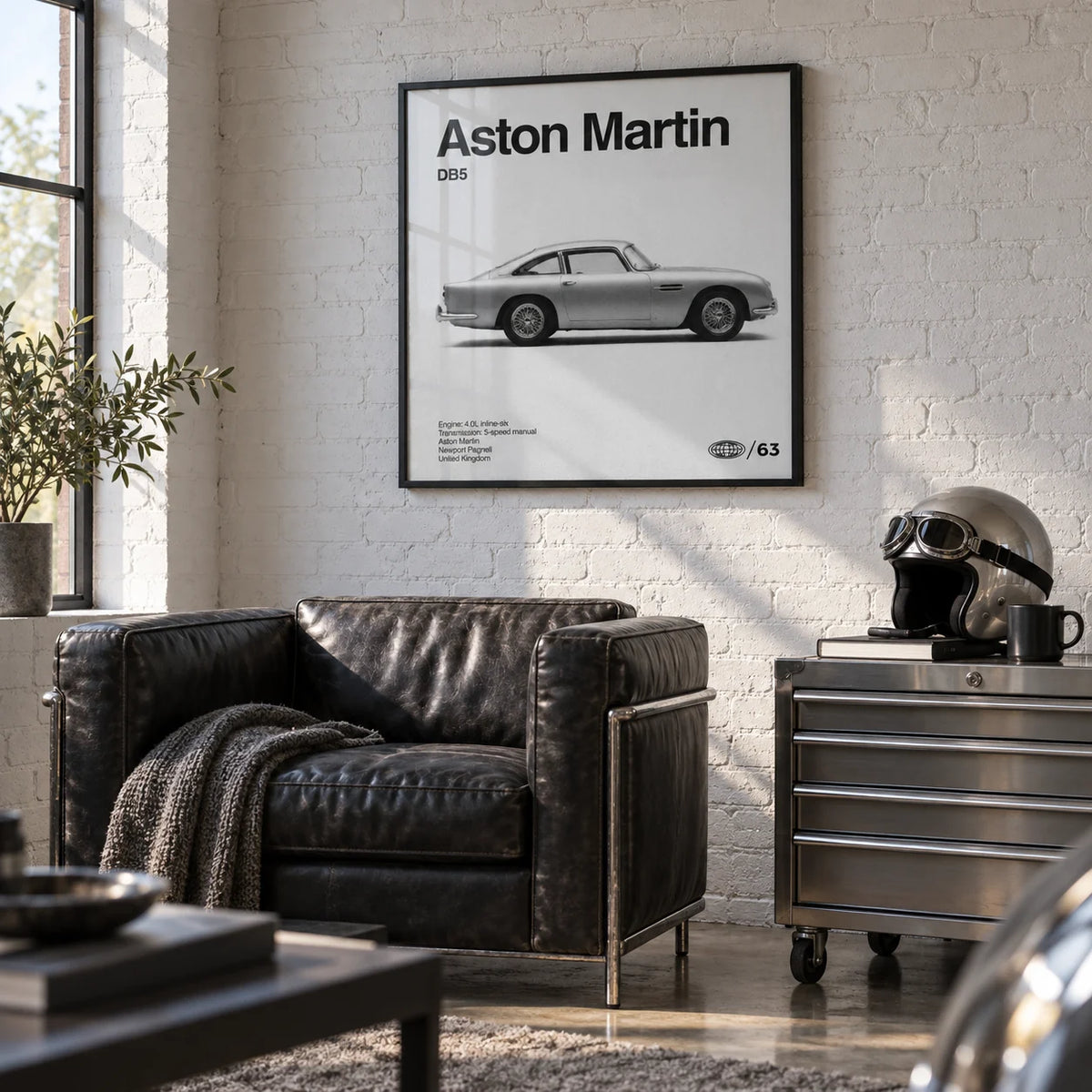 Classic British Grand Tourer Poster, framed on the wall of a stylish converted garage den with a white painted brick wall and a polished concrete floor in a living room