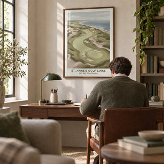 Coastal Golf Landscape, framed on the wall of a quiet golf enthusiast's home study with a pale stone wall and a low bookcase of clothbound books