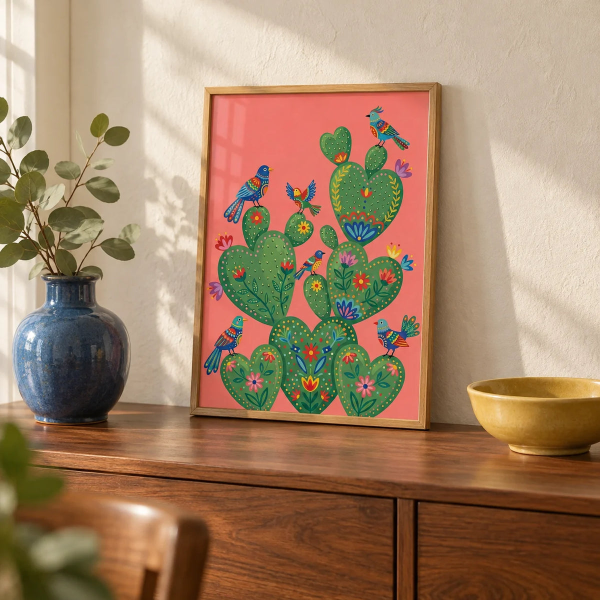 Colorful Cactus Art Print, a small A4 framed print leaning on a walnut sideboard in a living room