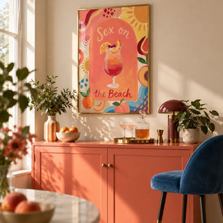 Colorful Drink Poster, framed on the wall of a compact home bar in a modern UK flat with a warm cream wall and a solid coral painted drinks cabinet in a living room