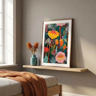 Framed colorful floral artwork on a wooden shelf in a bedroom.