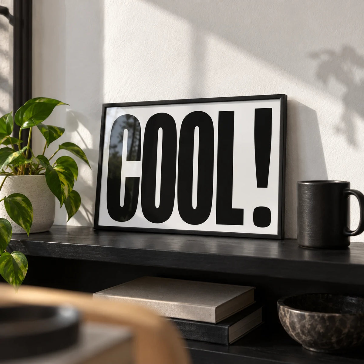 Cool Typography Poster, a small A4 framed print leaning on a black shelf in a living room