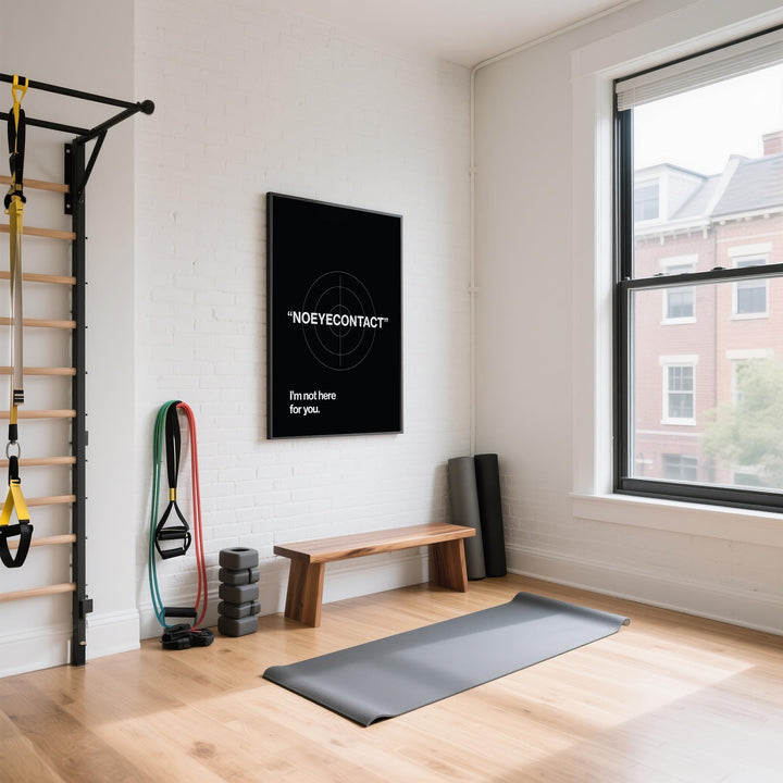 Gym art typographic phrase in white on black wall above wooden bench and exercise mat in a bright room