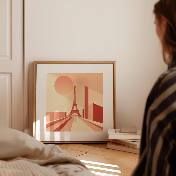 Eiffel Tower Poster Wall Art leaning on floor with warm orange tones next to books