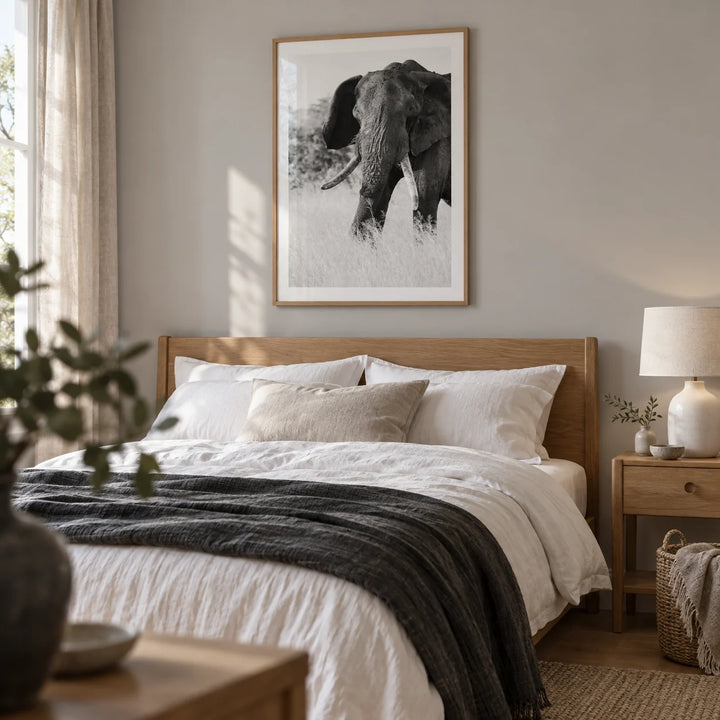 Elephant Black And White Art Print, framed on the wall of a restful adult bedroom with a pale grey wall and natural linen textures