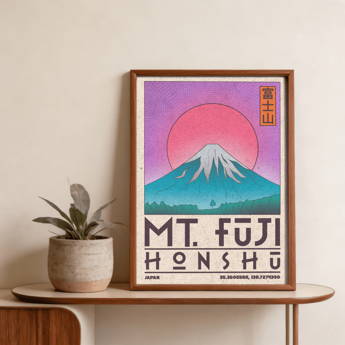Retro Mt Fuji travel poster in pink and teal leaning on a curved wooden console with a potted plant