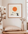 Two cats looking at an orange sun poster.