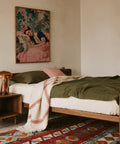 Frida Kahlo Art Prints showing painted portrait with green monstera leaves and floral pillows.