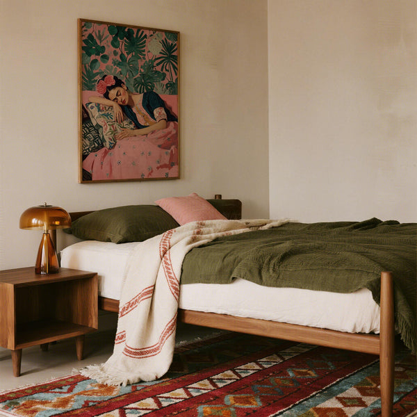 Frida Kahlo Art Prints showing painted portrait with green monstera leaves and floral pillows.